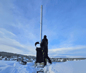 Installatør monterer rustfrie stålrør inne i en gammel skorstei