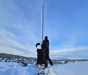 Installatør monterer rustfrie stålrør inne i en gammel skorstei