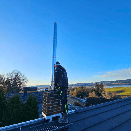 Arbeidere forbereder en skorstein før rehabilitering av pipe ved å fjerne skadede deler.