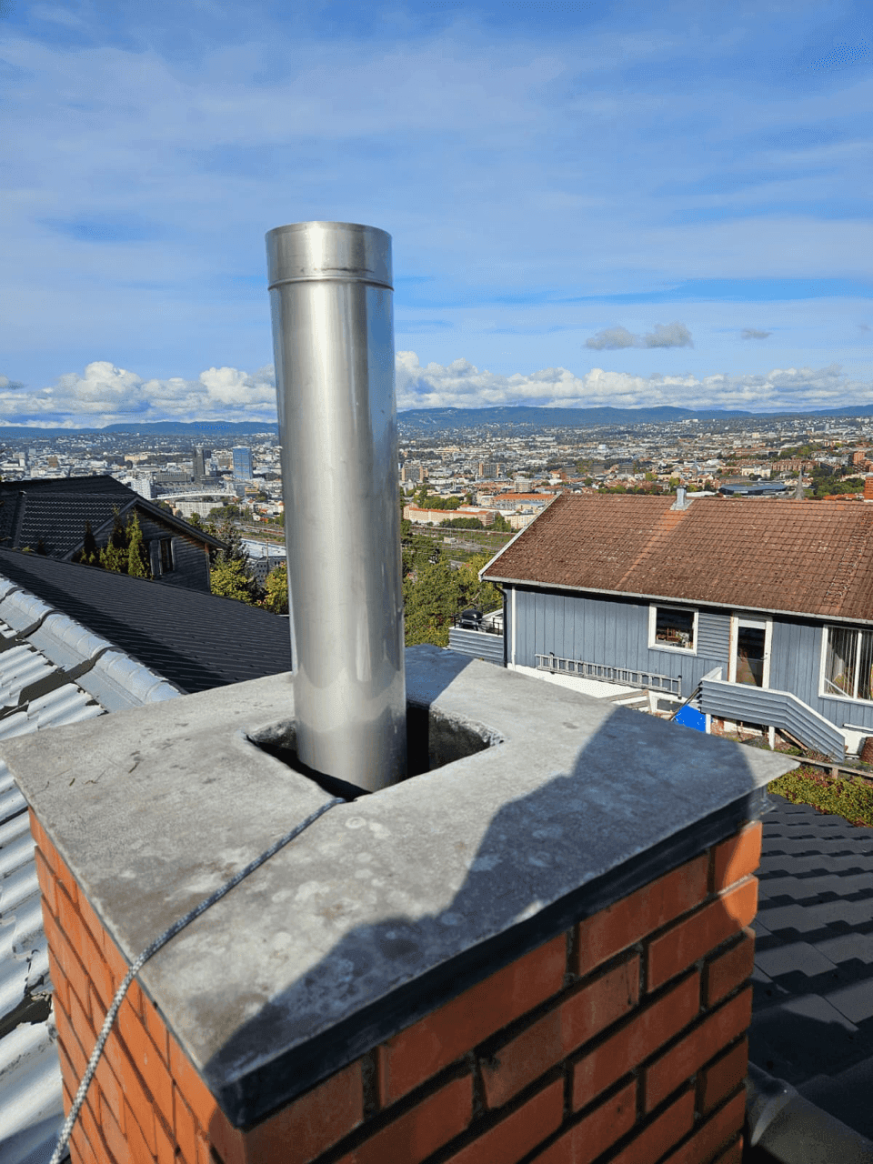 Et stålrør installert i en mursteinskorstein, nærbilde av installasjonen på taket.