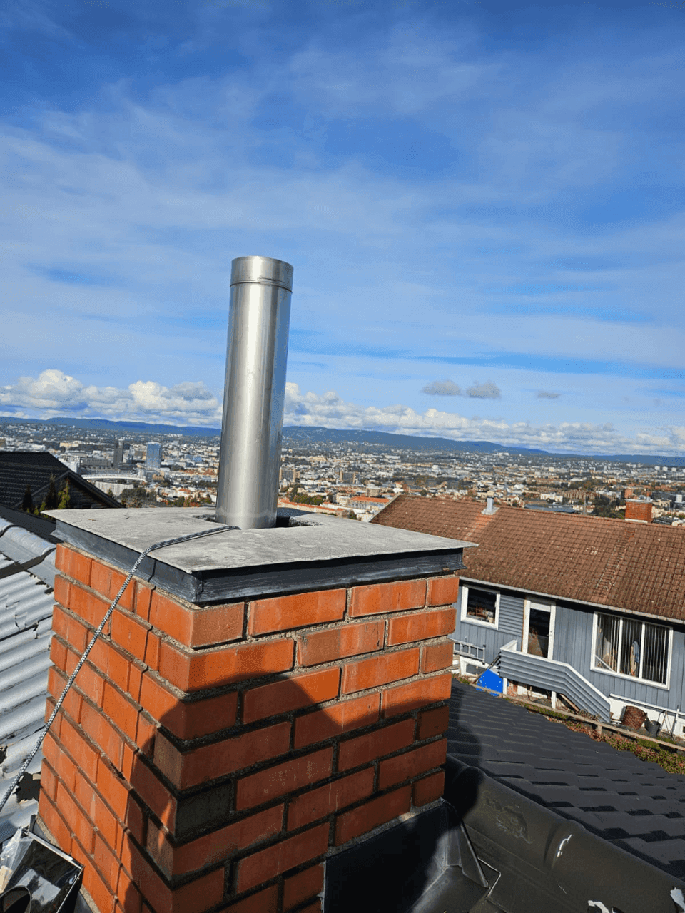 Nyinstallert stålrør i en mursteinskorstein, med panoramautsikt over byen i bakgrunnen
