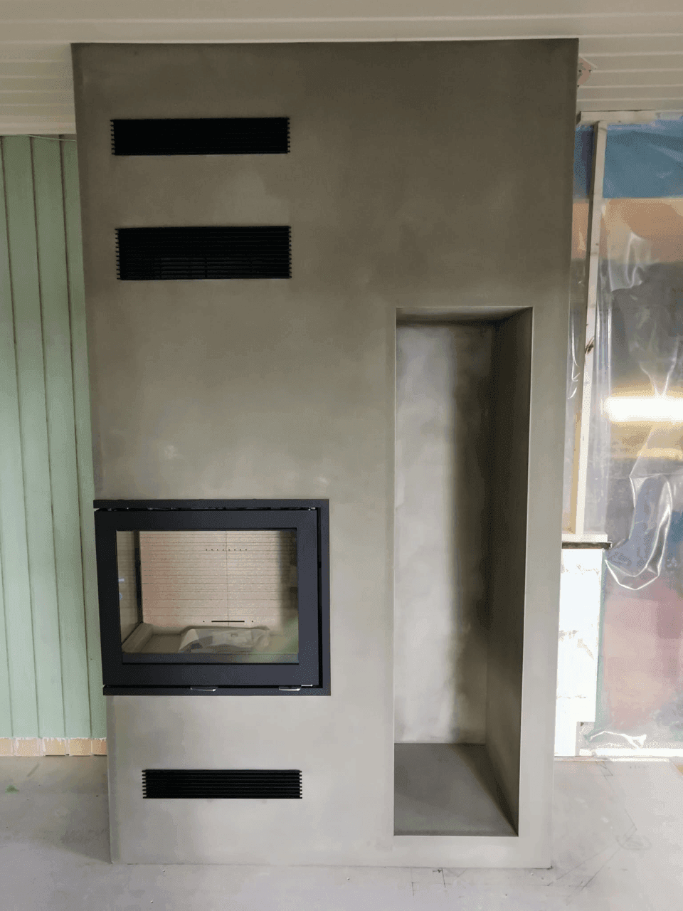 En hjørnepeis med moderne innbygging og glassfront, under arbeid i et nytt interiør.