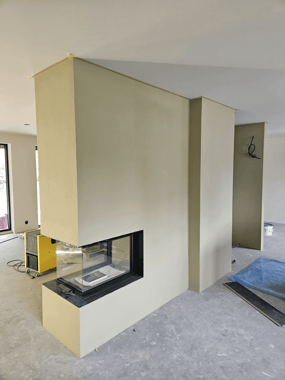 En moderne peisinnbygging med minimalistisk utførelse og svart peisramme, plassert i et lyst interiør.